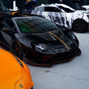 Black and orange luxury sports cars in a sleek, urban garage setting.