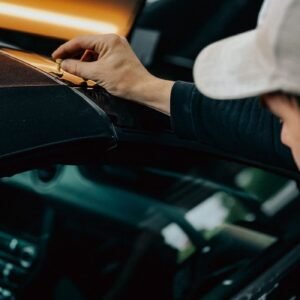 A professional detailing expert polishes a car in an automotive workshop, emphasizing quality craftsmanship.