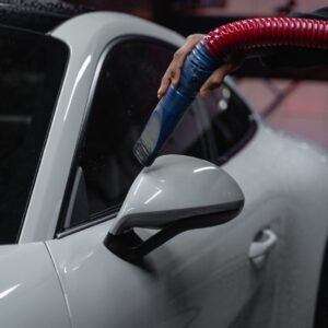 A white sports car is meticulously vacuumed indoors for a flawless shine and maintenance.